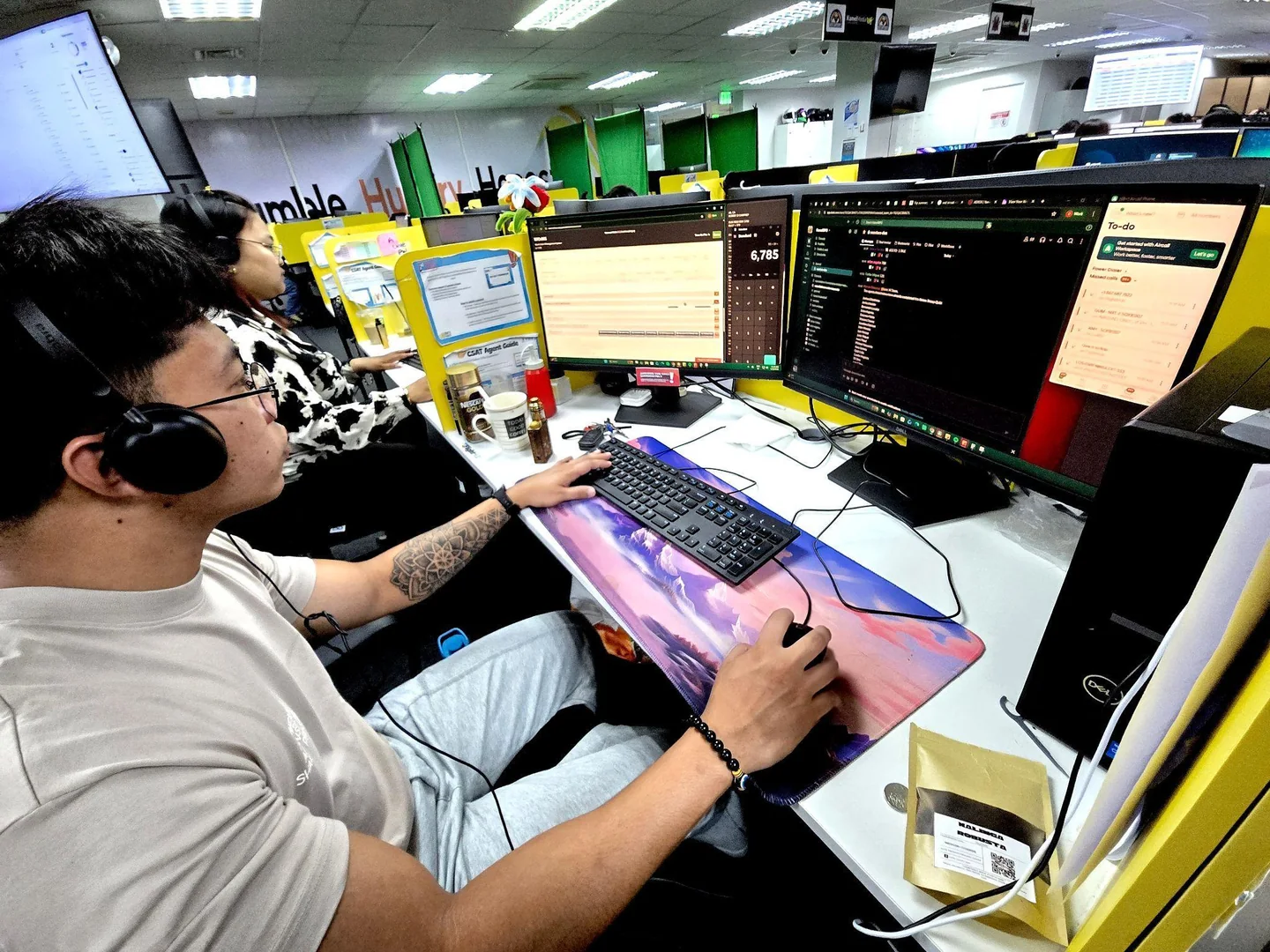 A KamelBPO colleague working at a dual-monitor desk with a colourful mousepad